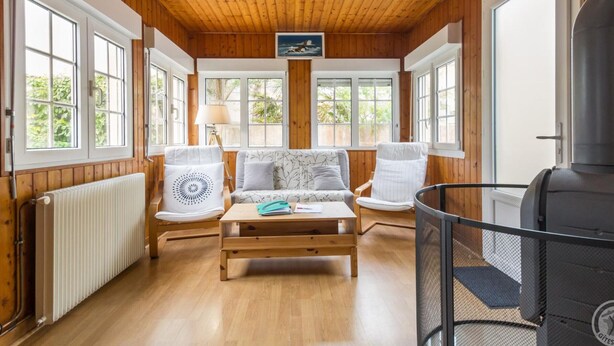 Una habitación acogedora con paredes y techo de madera, un conjunto de sofás, una mesa y una chimenea.