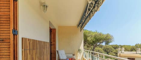 A balcony with a table set for two, a chair, and a small table lamp.