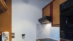 A kitchen with a built-in oven, a coffee maker, and a wall-mounted extractor hood. - Ski-in/ski-out apartment, view - 4 guests (Courchevel)