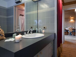 Ein Badezimmer mit einem großen Spiegel, einem weißen Waschbecken und einem roten Vorhang.