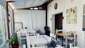 A dining area with white tables, potted plants, and a clock on the wall. - Isla Bella (Ushuaia)