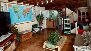 A living room with a wooden ceiling, a large world map, a television, and a sofa. - Isla Bella (Ushuaia)