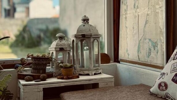 A room with a bed, a small table with decorative items, a window with a view of buildings, and a map on the wall. - Isla Bella (Ushuaia)