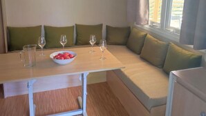 A corner seating area with a table, a bowl of fruit, and wine glasses. - Mobile home, pets allowed - 4 guests (Estaing)