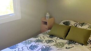 A bedroom with a bed, a nightstand, a window, and a cabinet. - Mobile home, pets allowed - 4 guests (Estaing)