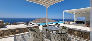 Un área de estar al aire libre con piscina, paredes de piedra y vista al mar.