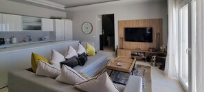 Una sala moderna con un sofá, una mesa de centro y un televisor de pantalla plana.