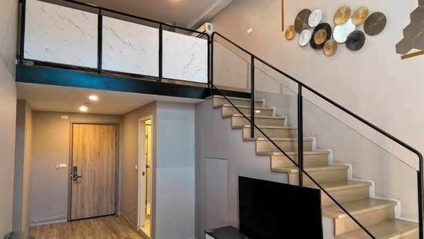 Un salon moderne avec un téléviseur, un canapé et un escalier.