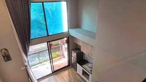 Un appartement moderne doté d’un balcon, d’un canapé, d’un coin repas et d’un escalier.