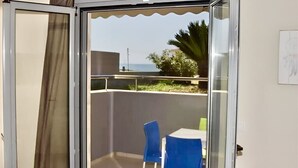 Ein Balkon mit Glastür, Tisch und zwei Stühlen.