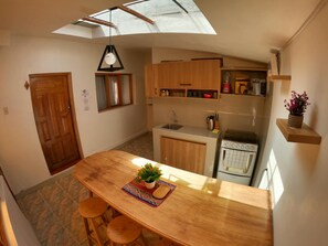 A compact kitchen with wooden cabinets, a built-in oven, and a skylight. - EKEKOS CUSCO (Cusco)