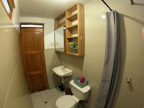 A compact bathroom with a wooden door, a sink, a toilet, and a shower curtain. - EKEKOS CUSCO (Cusco)
