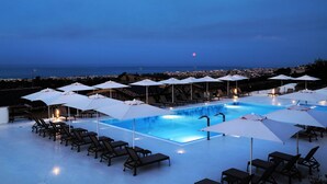 A rooftop pool with lounge chairs and umbrellas, overlooking a cityscape at dusk. - Garden View Apartment by Parco Valle Della Civita (Colonnella)
