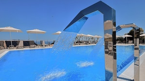 A swimming pool with clear blue water, surrounded by lounge chairs and umbrellas. - Garden View Apartment by Parco Valle Della Civita (Colonnella)