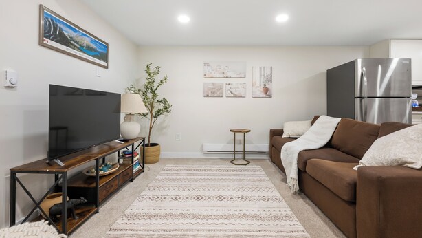 A living room with a flat-screen TV, a brown sofa, a coffee table, and a decorative plant.