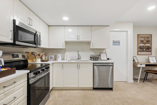 A modern kitchen with white cabinets, stainless steel appliances, and a dishwasher. - Pristine Suite Near Fish Creek Park & Horse Events (500 Mbps WiFi + Workspace) (Calgary)