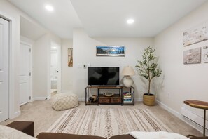A living room with a flat-screen TV, a lamp, a potted plant, and a framed picture on the wall.