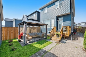 A backyard with a covered patio, outdoor furniture, a barbecue grill, and a wooden deck. - Pristine Suite Near Fish Creek Park & Horse Events (500 Mbps WiFi + Workspace) (Calgary)