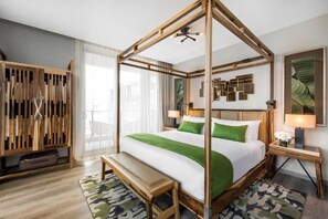 Ein Hotelzimmer mit Himmelbett, Holzschrank, einer Bank und einem gemusterten Teppich.