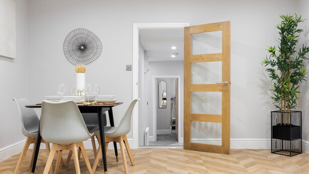 A dining area with a table set for four, a modern wall art piece, and a wooden door leading to another room. - Conveniently Situated - Luxuriously Furnished! (London)