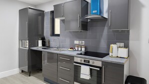 A modern kitchen with grey cabinets, a stainless steel sink, and a built-in oven. - Conveniently Situated - Luxuriously Furnished! (London)
