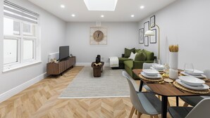 A modern living room with a dining area, a television, and a sofa. - Conveniently Situated - Luxuriously Furnished! (London)