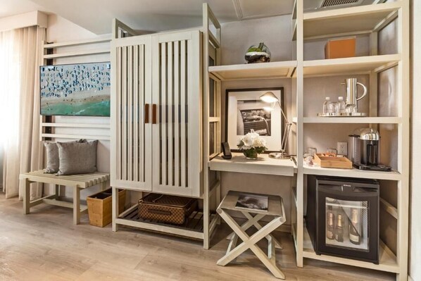 Ein modernes Zimmer mit integriertem Schreibtisch, Regalen und einem kompakten Kühlschrank.
