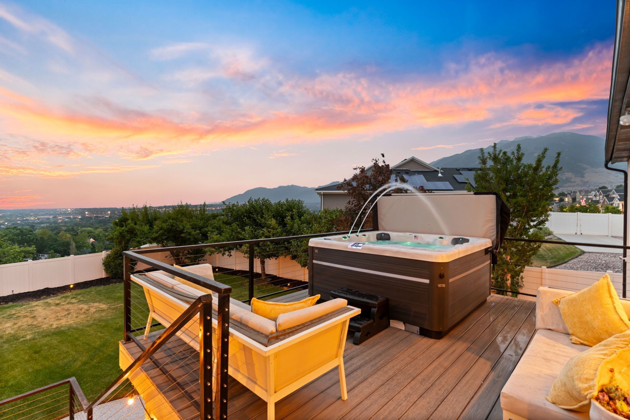 A deck with a hot tub, outdoor seating, and a scenic view of mountains.