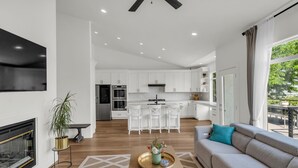 Een moderne woonkamer met een open haard, een bank, een salontafel en uitzicht op de keuken en eetruimte.