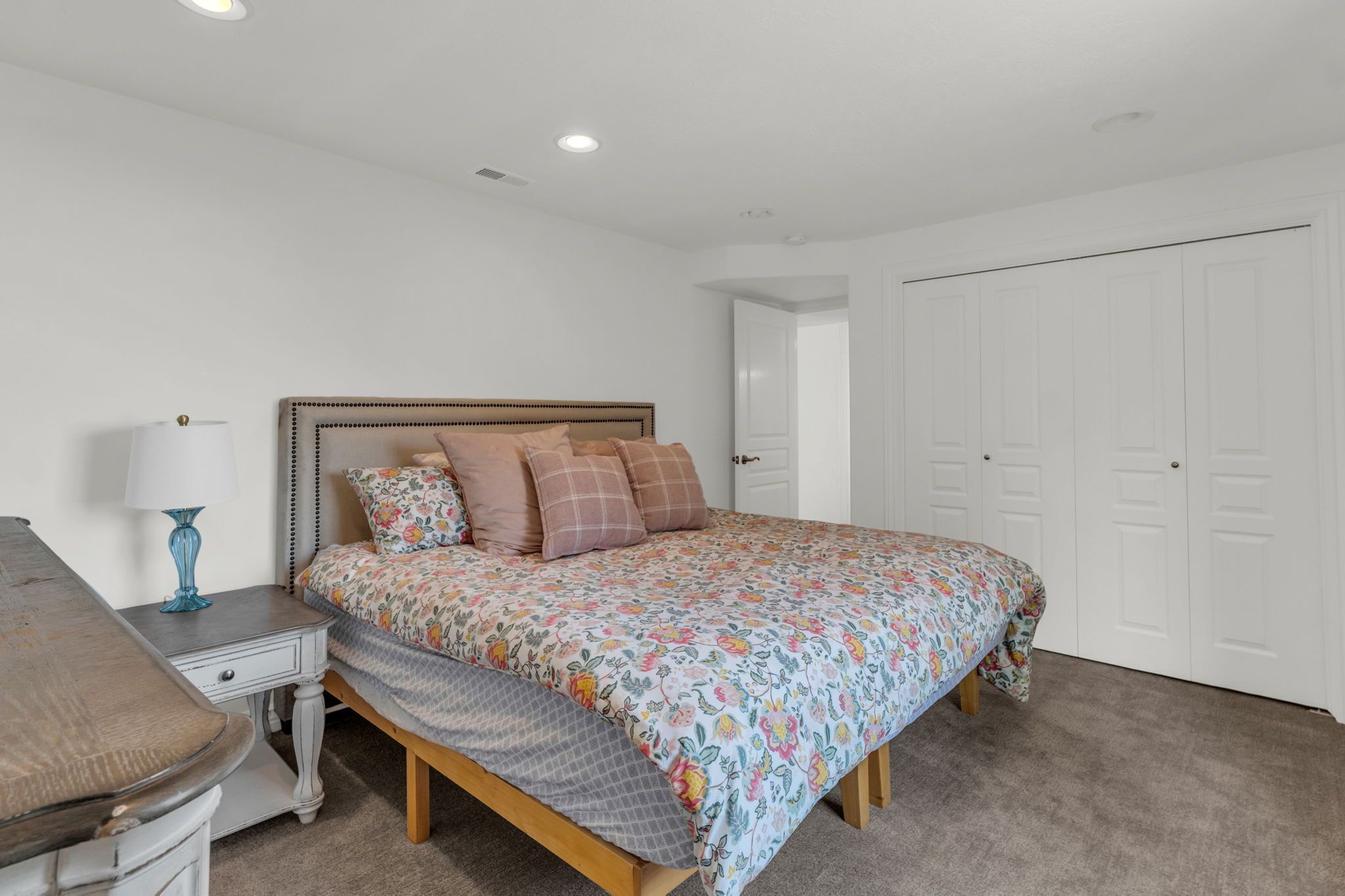 Quarto com cama, mesa de cabeceira, luminária e guarda-roupa.