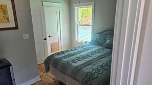 Een slaapkamer met een bed, een raam en een deur.