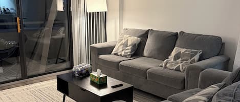 A modern living room with a grey sofa, a black coffee table, and a striped curtain.