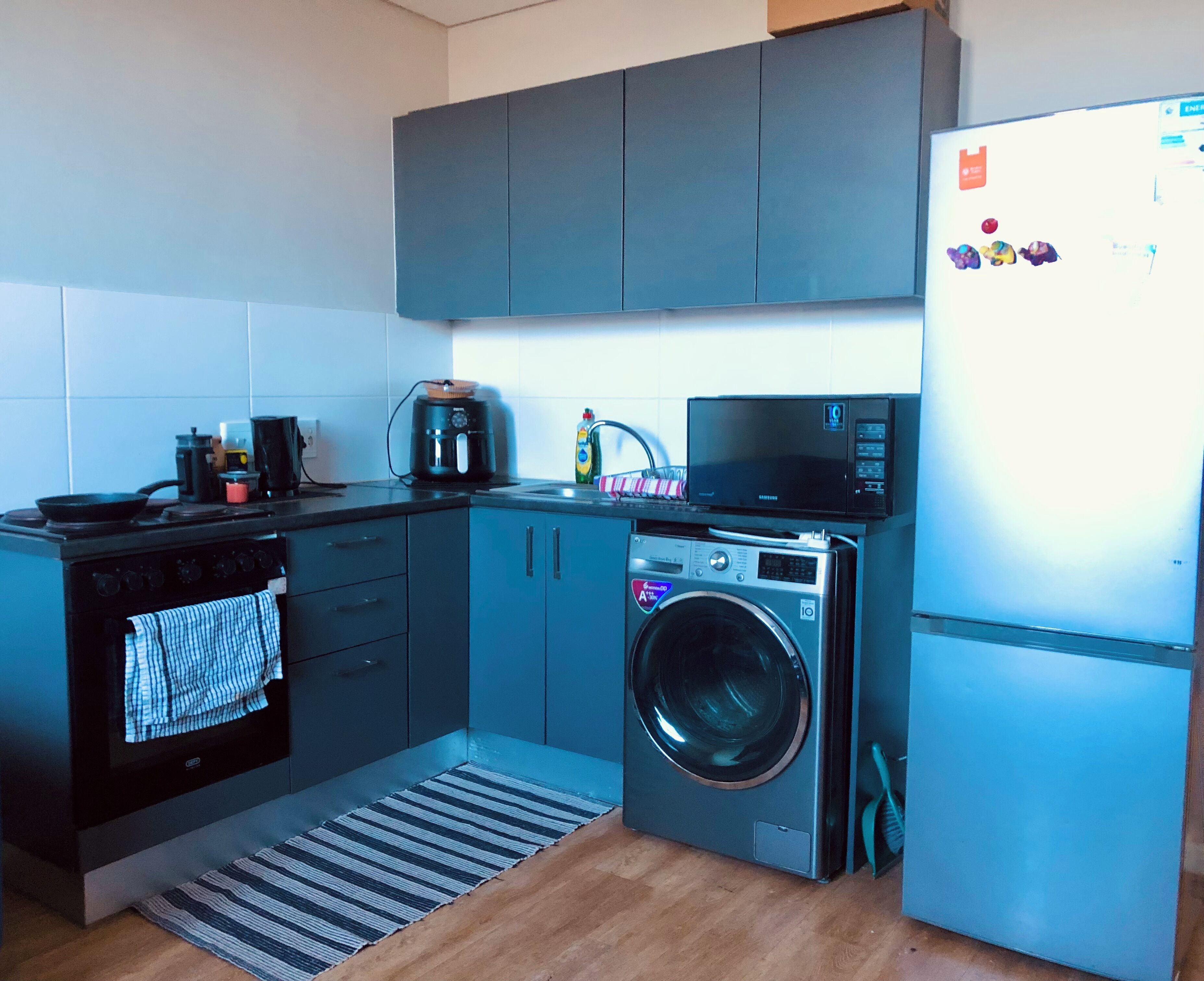 A compact kitchen with a stove, microwave, and washing machine.
