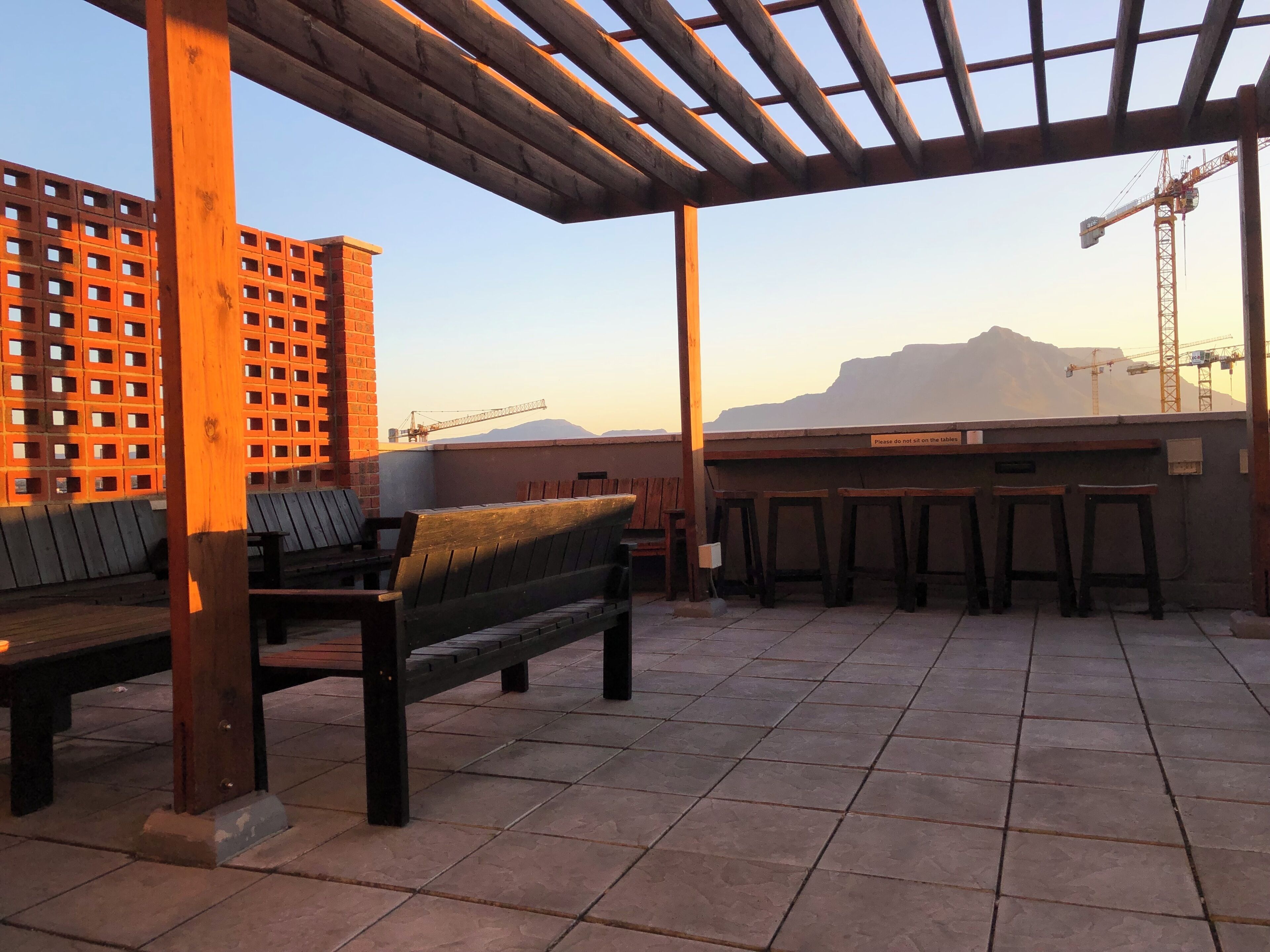 En takterrass med en träbänk, ett bord och utsikt över berg i bakgrunden.