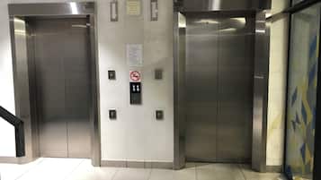 Een paar liftdeuren met een bedieningspaneel en noodinstructies.