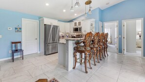 A kitchen with a central island, stainless steel appliances, and a dining area with ornate chairs. - The Flying Mermaid (Edgewater)