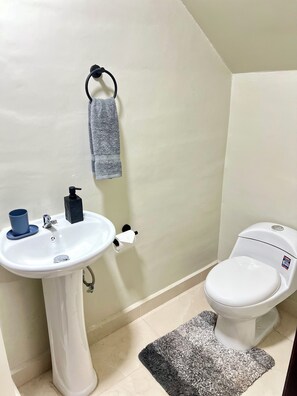 A bathroom with a white sink, toilet, and a towel hanging on the wall.