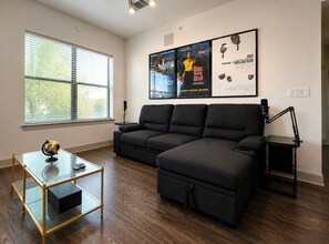 A living room with a sectional sofa, a glass coffee table, and a black floor lamp.