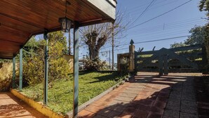 A covered outdoor area with a brick pathway leading to a gated entrance. - Casa em Campos do Jordão com Lareira (Campos do Jordão)
