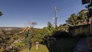 A residential area with a view of a valley, a birdhouse, and a stone bench. - Casa em Campos do Jordão com Lareira (Campos do Jordão)