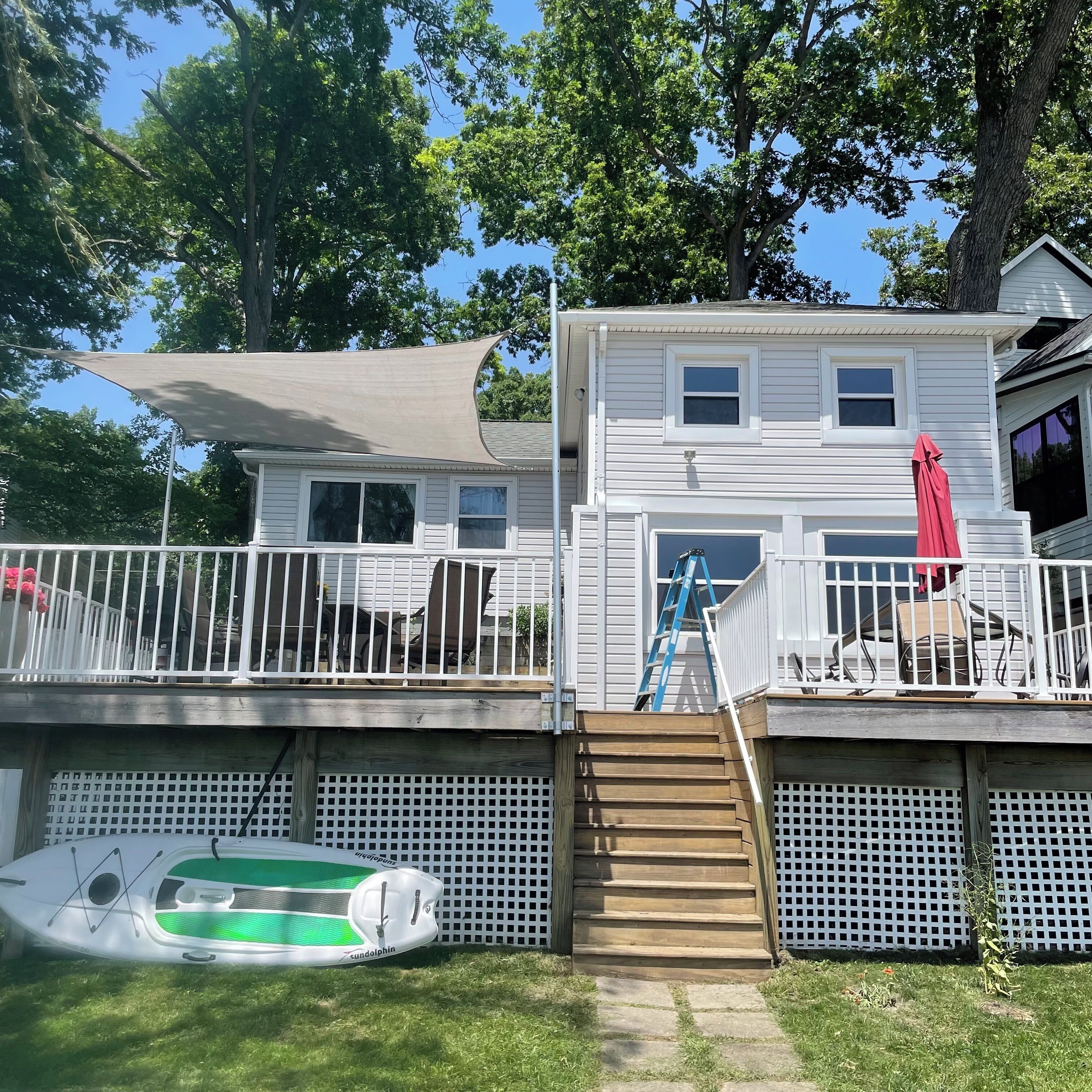 Une maison à deux étages avec une terrasse, une échelle et un flotteur pour la piscine.