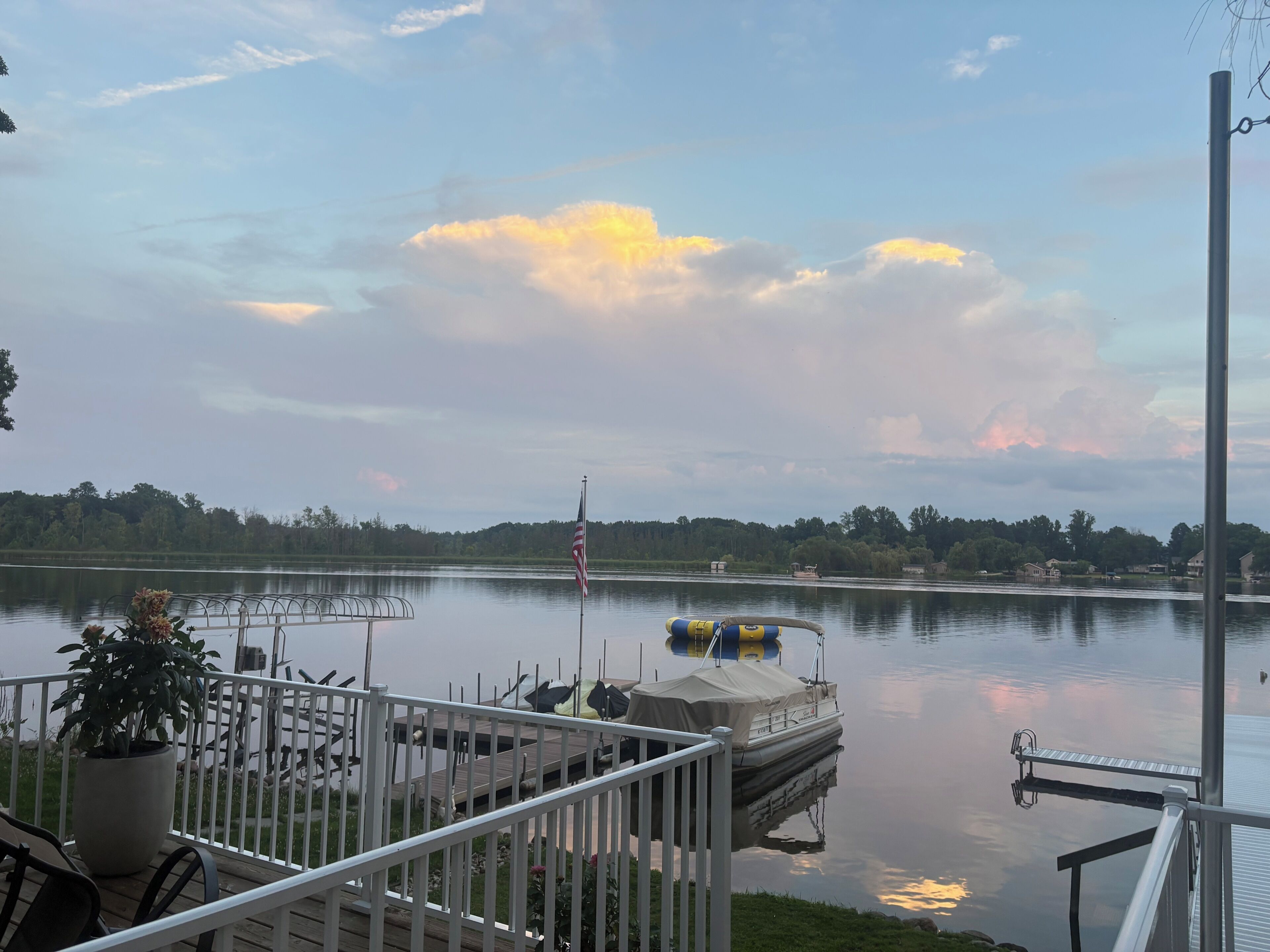 Un lac paisible, avec un quai, un bateau et un drapeau.