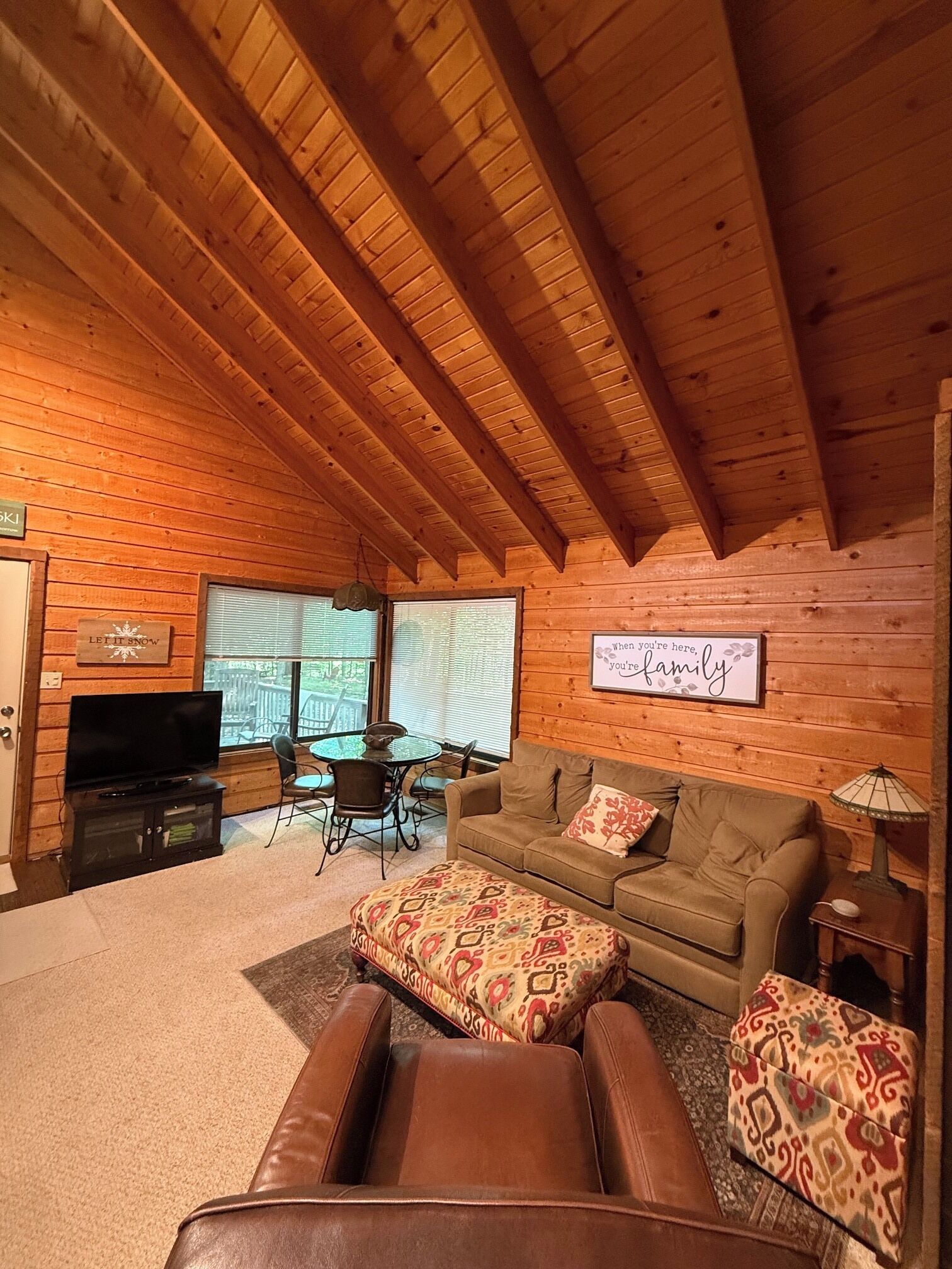 Ein gemütliches Blockhaus-Interieur mit Sofa, Hocker und Fernseher.