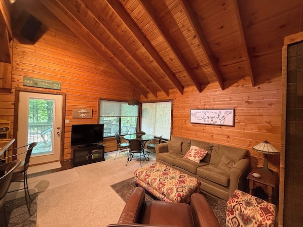 A cozy wooden cabin interior with a television, sofa, and dining area.