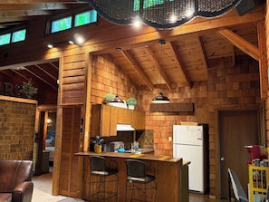 A wooden interior with a bar area, kitchen, and seating.
