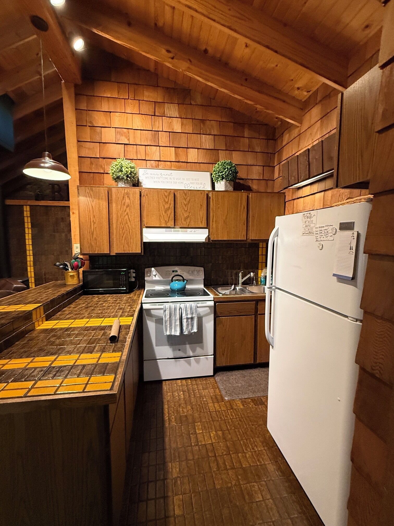 Una cocina con armarios de madera, estufa, lavabo y refrigerador.