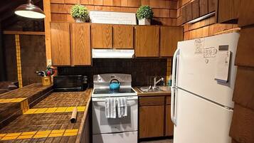 Una cocina con armarios de madera, estufa, lavabo y refrigerador.