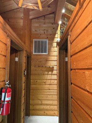 A narrow wooden hallway with a fire extinguisher mounted on the wall.