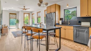 Une cuisine moderne dotée d’un îlot central, de meubles en bois, d’un réfrigérateur en acier inoxydable et d’un lave-vaisselle.