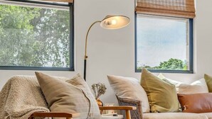 Una sala de estar acogedora con un sillón de cuero, un reposapiés verde y una lámpara de pie.